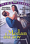 Omslag Medan du sov där Bill Pulman lyfter Sandra Bullock vid en tågstation