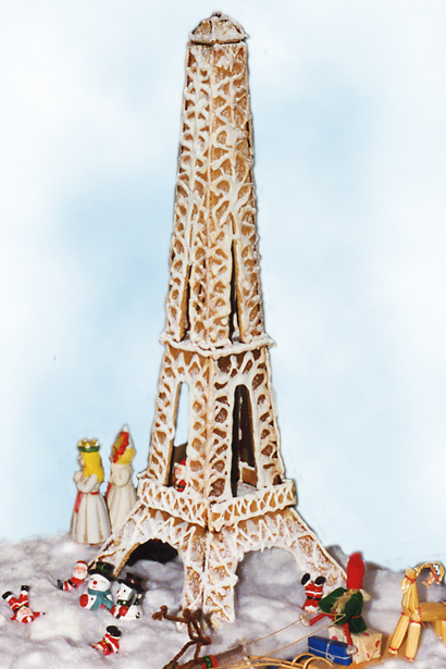Foto av pepparkakshusi form av Eiffeltornet, omringat av tomtar, luciatåg med mera