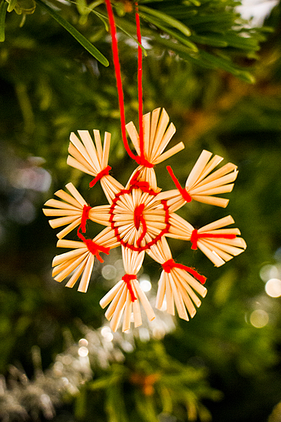 Foto av julgranspynt i en julgran: stjärna av halm med röda snören