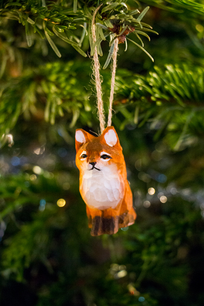 Närbild av julgranspynt, en liten räv. I bakgrunden: julgranens grenar.
